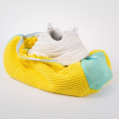 Yellow shoe bag with a white sneaker inside on a light gray background